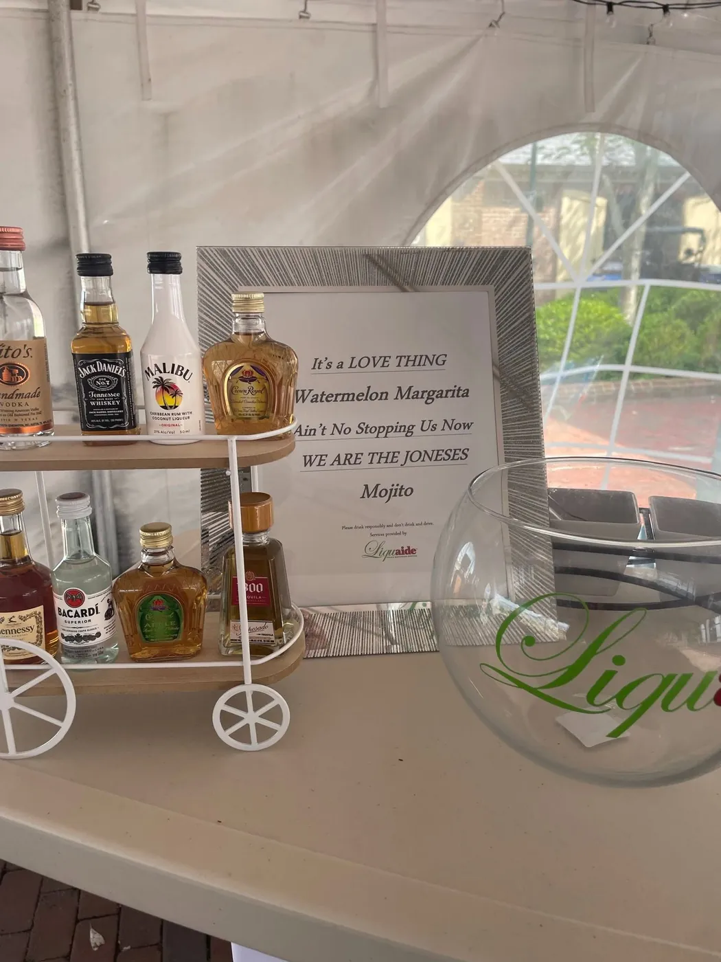 Mini bar cart with a curated liquor selection and custom event playlist sign