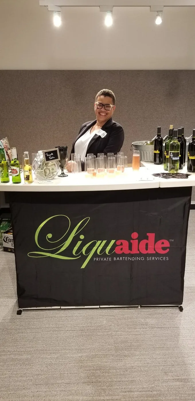 Sonya Daniels, owner and certified mixologist of Liquaide, smiling behind the bar at a private event